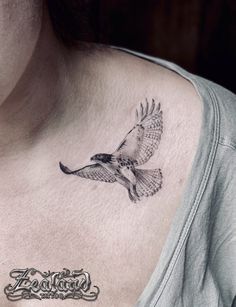 a woman's chest with a bird tattoo on it