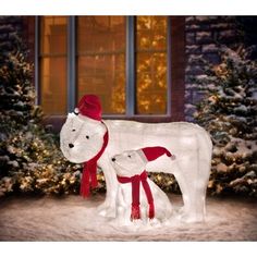 a white polar bear and her cub are standing in front of a house decorated for christmas