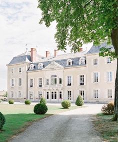 a large white building sitting next to a lush green field