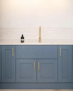 a kitchen with blue cabinets and white counter tops, gold faucet on the sink