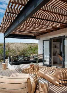 an outdoor living area with couches and pillows under a pergolated roof over looking the ocean