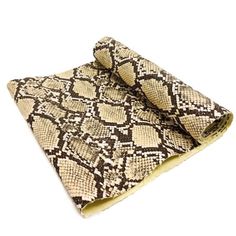 a brown and white snake skin blanket folded on top of a white surface with the end rolled up