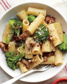 a bowl filled with pasta and broccoli on top of a white table cloth