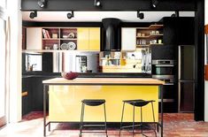 a kitchen with two stools next to an island in the middle of the room