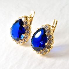 Gold Sapphire Earrings set with Created Sapphire in a flawless clarity, pear diamond cut & stunning royal blue color, at 16x12mm each surrounded with Created CZ Diamonds at 3mm each (22 Cts a pair) Gold Vermeil: 18k Gold over Solid 925 Sterling Silver ☞ made to last. Matching Pendant: www.etsy.com/listing/958926549 Matching Ring: www.etsy.com/listing/780193095 For Pierced Ears - has a pin that goes into the ear and a leaver that securely closes on the pin behind the earlobes - "English Lock" Details : ♥ Each item comes in a cute GIFT BOX ✓ ♥ GUARANTEE on all materials ✓ ♥ Created Sapphire in a flawless clarity & CZ Diamonds ✓ ♥ 18k Gold over Solid 925 Sterling Silver ✓ ♥ Measurements: Sapphire size 16x12mm each & CZ Diamonds at 3mm each, 22 Carats a pair✓ ♥ Each stone set professionally - Diana Earrings, Large Statement Earrings, Cute Gift Boxes, Matching Ring, Earrings Large, Royal Blue Color, Matching Rings, Sapphire Earrings, Pear Diamond