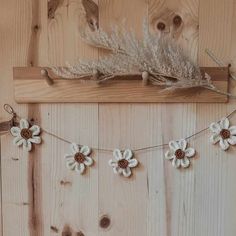 white flowers are hanging on a wooden wall