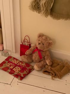 a teddy bear sitting on the floor next to a red bag