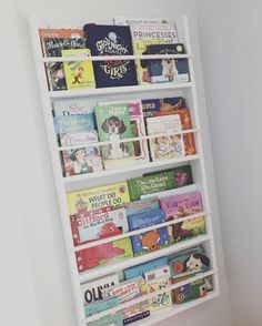 a white book shelf filled with lots of children's books next to a wall