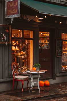 an outdoor cafe with tables and chairs in front of the storefront, outside at night