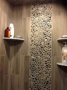 an image of a bathroom with pebbles on the shower wall and shelfs above it