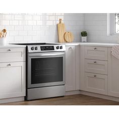 a kitchen with white cabinets and stainless steel stove top oven in front of the counter