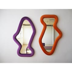 an orange and purple mirror sitting on top of a wall next to a white wall