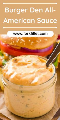 a jar filled with sauce sitting on top of a cutting board next to a burger