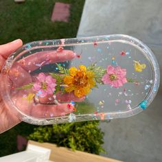 a hand holding a clear case with flowers and confetti on the bottom half