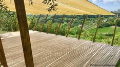 an outdoor area with wooden decking and large yellow umbrellas on the top of it