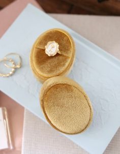 two small round cakes sitting on top of a white tray next to a pair of earrings