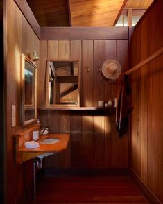 a bathroom with wood paneling and two sinks in the corner, one has a hat on top of it