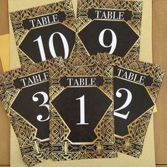 four black and gold table numbers are on top of each other, with an intricate design