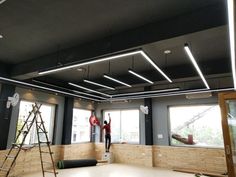 a man is standing on a ladder in the middle of an empty room with windows