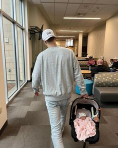 a man walking with a stroller and baby in it's hand through an office building