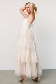 a woman in a white dress posing for the camera with her hand on her head