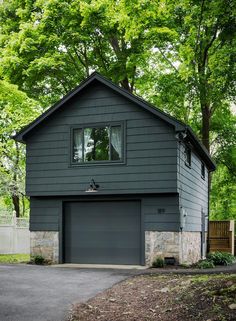 a house with a garage in front of it and lots of trees around the yard