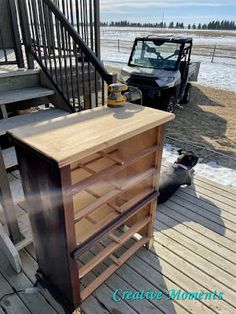 a wooden dresser sitting on top of a wooden deck next to a metal hand rail