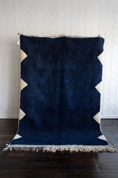 a blue and white rug sitting on top of a wooden floor next to a wall