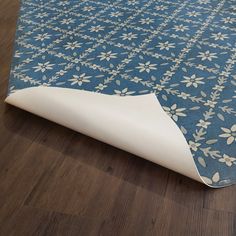 a blue and white rug on the floor next to a wooden floor with a pillow