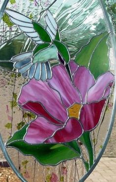 a close up of a stained glass window with flowers in the center and a humming on it