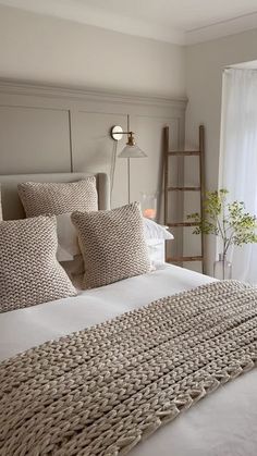 a bed with white linens and pillows in a bedroom next to a large window