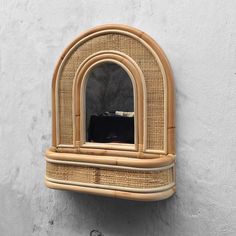 a small window on the side of a white wall with a rattan frame around it