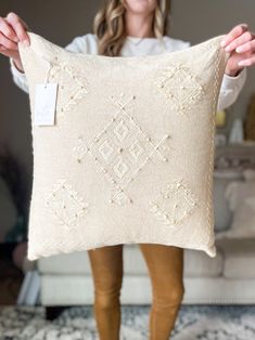 a woman holding up a decorative pillow