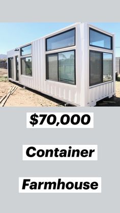 a white container house sitting on top of a dirt field next to a building with windows