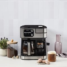 a coffee maker sitting on top of a counter next to some cups and saucers