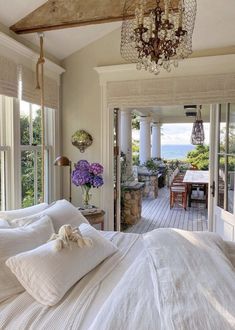 a bedroom with a bed, chandelier and large windows overlooking the outdoors area