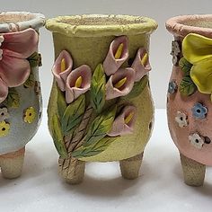 three ceramic vases with flowers painted on them