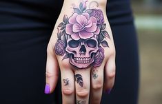 a woman's hand with a skull and flowers tattooed on it