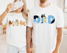 a man and woman standing next to each other wearing matching t - shirts with the word dad printed on them