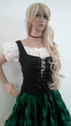 a mannequin wearing a green and black dress with long blonde hair in front of a white wall