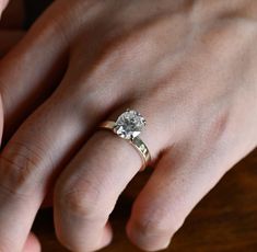 a woman's hand with a diamond ring on top of her finger and an engagement band