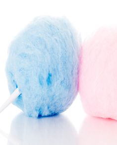 two blue and pink wool balls on a white surface with a toothbrush in the middle