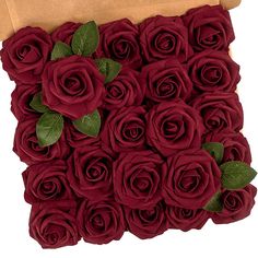 a bunch of red roses sitting on top of a piece of cardboard with green leaves