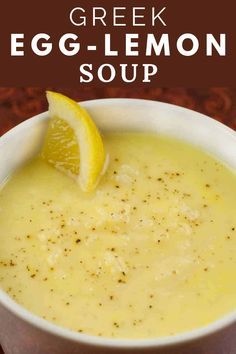 a white bowl filled with egg - lemon soup on top of a wooden table next to an orange slice