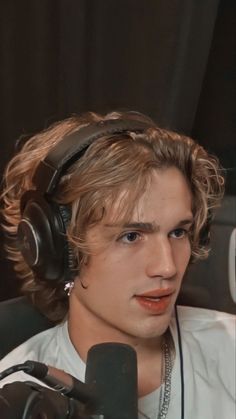 a young man with headphones on sitting in front of a microphone