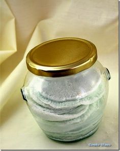 a glass jar filled with lots of white sand sitting on top of a tablecloth