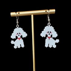 a pair of beaded earrings with a poodle on the front and back of it