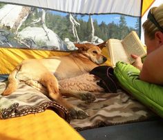 a woman reading a book to her dog