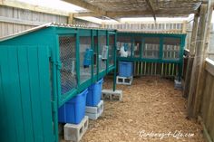 the inside of a chicken coop with blue bins