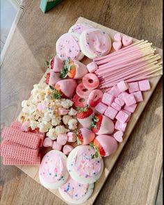 a wooden table topped with lots of pink and white treats